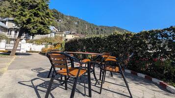 Un espacio al aire libre con suelo de losas de piedra, sillas y mesas de madera.