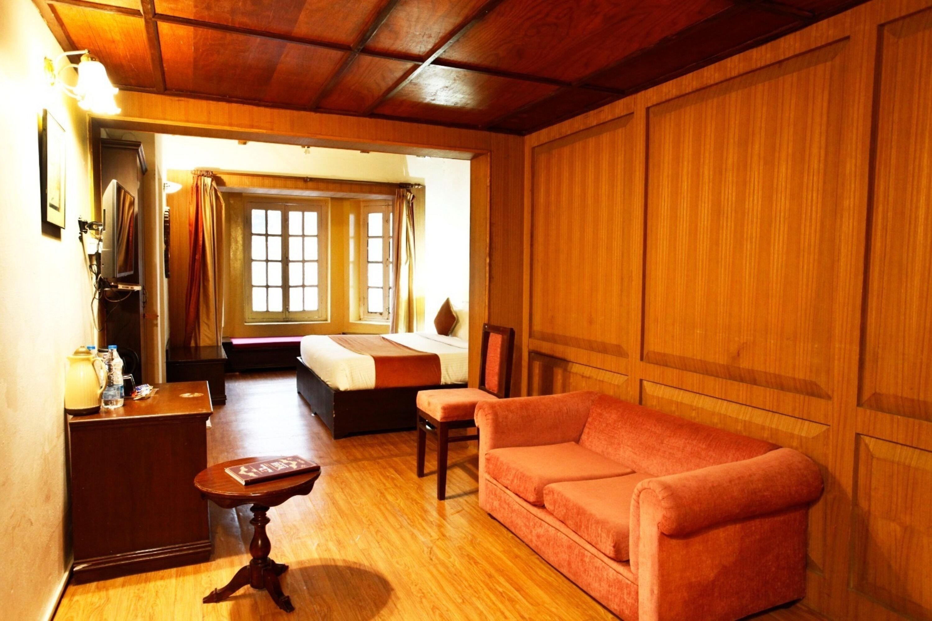 Ein gemütliches Zimmer mit Holzbalkendecke, einem Bett mit Blick, einem roten Sofa und einem kleinen Tisch.