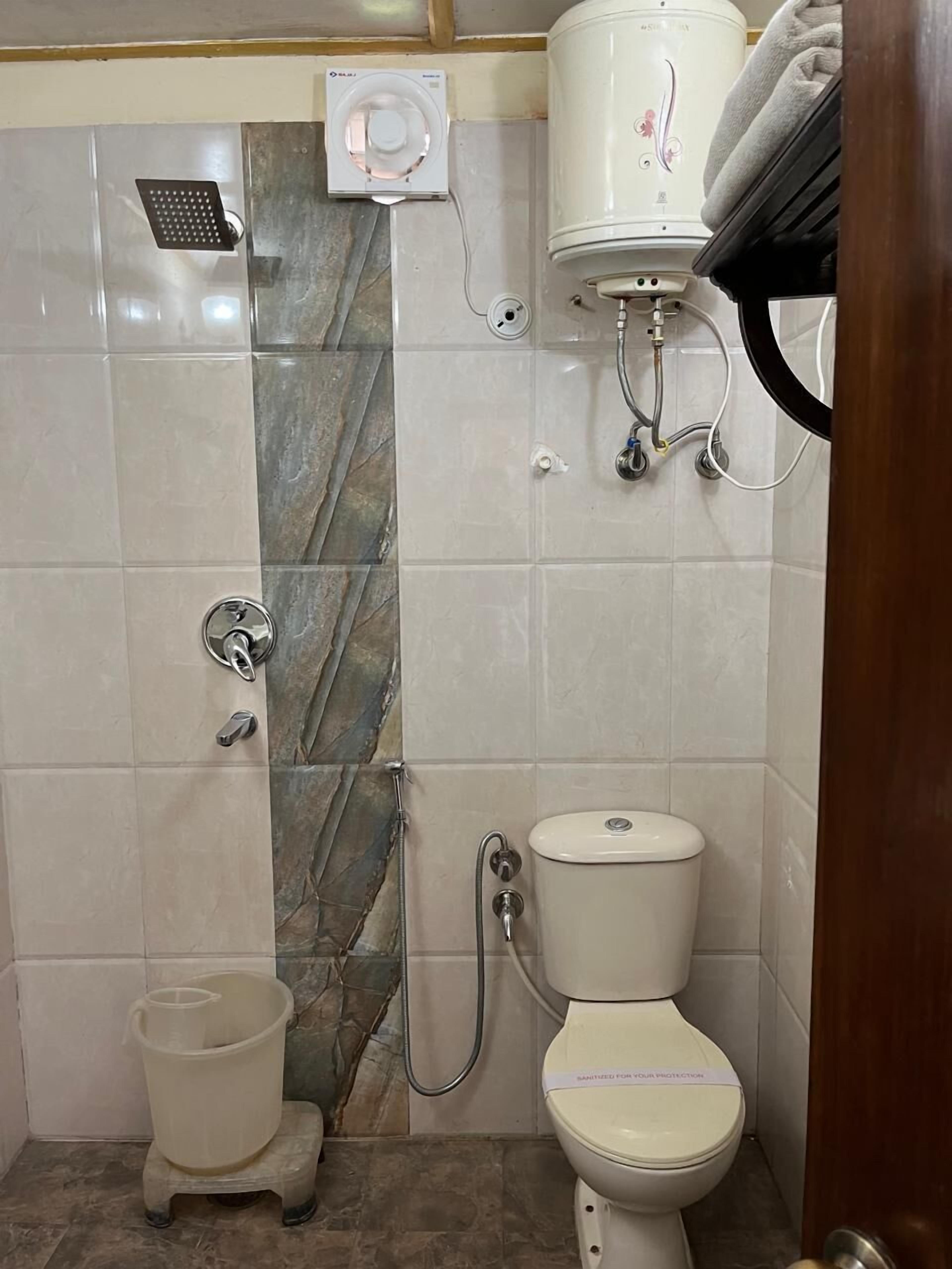 Un baño con ducha, inodoro y calentador de agua.