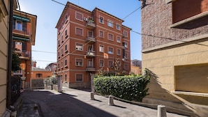 Une rue étroite bordée d’un immeuble à plusieurs étages, doté de balcons et de fenêtres.