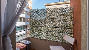 Un balcon avec une rambarde en treillis, une chaise et une petite table avec un coussin.
