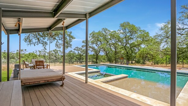 Une terrasse en bois avec une piscine, des chaises longues et un espace salon abrité.