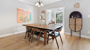 Un espace repas comprenant une table et des chaises en bois, un lustre et des œuvres d’art murales.