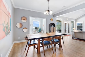 Enjoy meals in this dining area with a long table and six chairs, surrounded by a high ceiling and circular wall art.