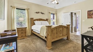 A bedroom with a wooden bed, a ceiling fan, a nightstand, a dresser, and a bookshelf. - Copper Canyon Hideaway + Free Retro Arcade Fun (Canyon Lake)