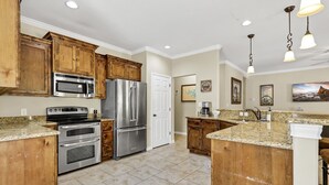 A kitchen with wooden cabinets, stainless steel appliances, granite countertops, and pendant lighting. - Copper Canyon Hideaway + Free Retro Arcade Fun (Canyon Lake)