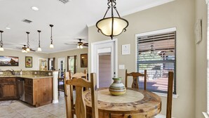 A spacious kitchen with a large island, wooden chairs with cushions, and a round dining table with a decorative vase. - Copper Canyon Hideaway + Free Retro Arcade Fun (Canyon Lake)