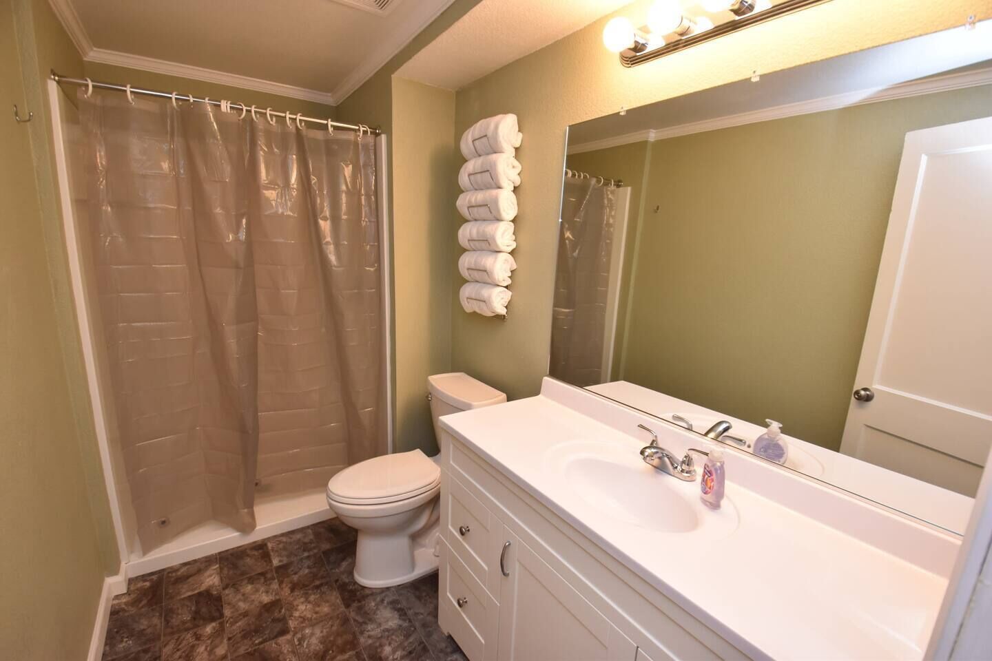 A bathroom with a shower curtain, toilet, sink, and a mirror.