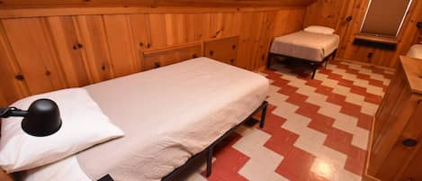 Una pequeña cabaña de una sola habitación, con una cama, una mesita de noche y un escritorio.
