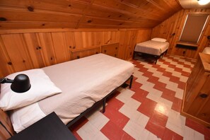 Una pequeña cabaña de una sola habitación, con una cama, una mesita de noche y un escritorio.