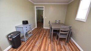 A dining area with a table and chairs, a trash bin, and a hallway leading to another room. - 20 min Walk to ND, 3 bedroom 2 bath home(54475) (South Bend)