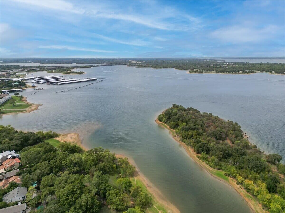 Vista aérea de una gran masa de agua con un muelle y una zona boscosa.