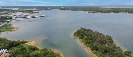 Vista aérea de una gran masa de agua con un muelle y una zona boscosa.