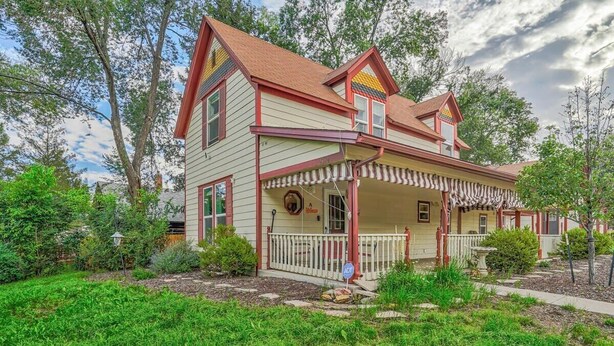 Ein zweistöckiges Haus mit Veranda, umgeben von viel Grün.