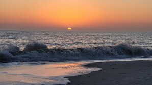 Una playa al atardecer con olas rompiendo en la orilla.