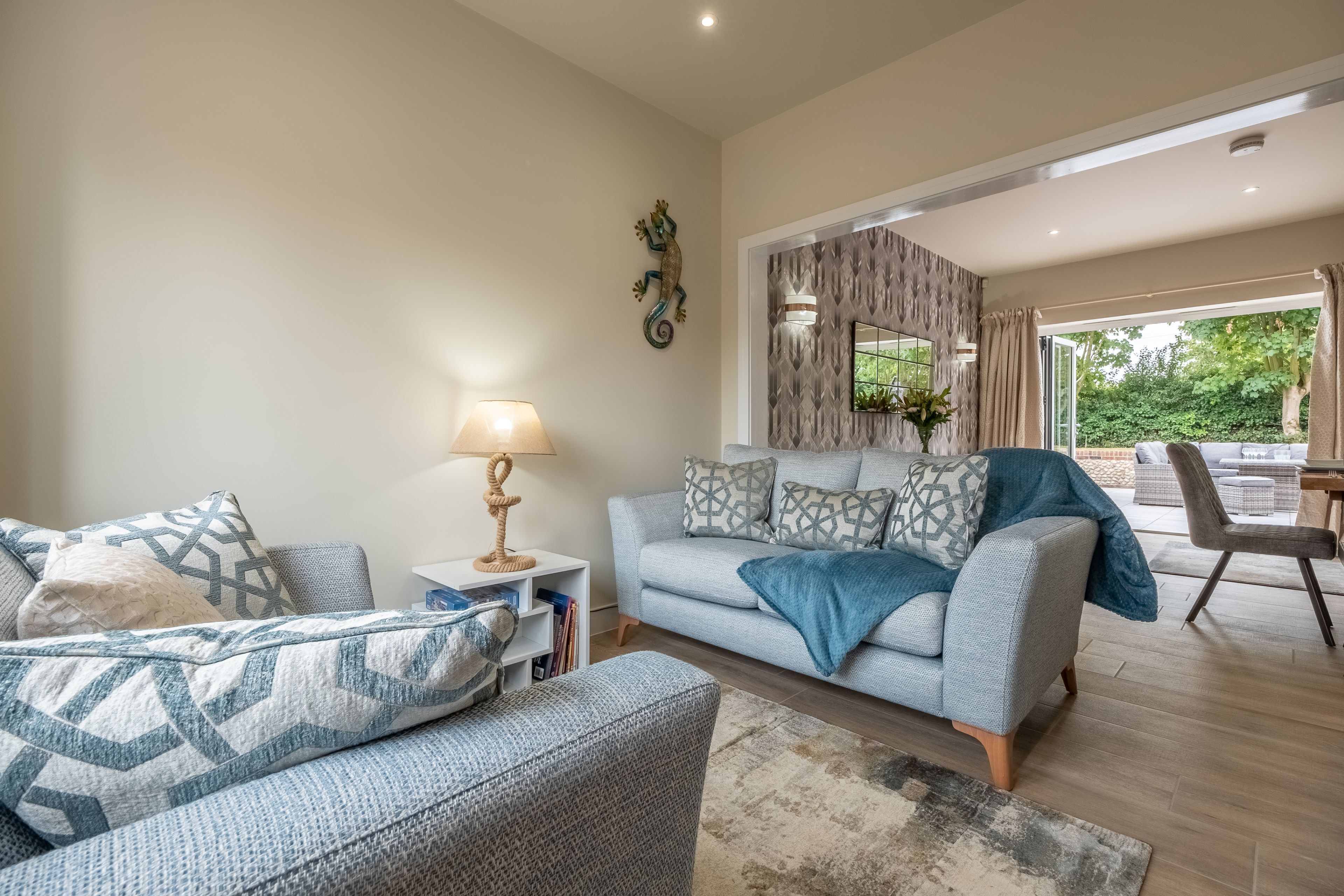 Un salon moderne avec un canapé, une table basse et une lampe. Une fenêtre offre une vue sur la verdure à l’extérieur.