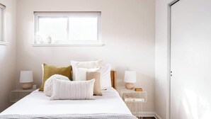 A bedroom with a bed, two bedside tables, a window, and a door. - Chic Mid-Century Home Near Olde Town Arvada (Arvada)