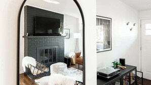 A living room with a fireplace, a television, and a mirror archway. - Chic Mid-Century Home Near Olde Town Arvada (Arvada)