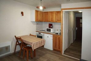 A compact kitchen with wooden cabinets, a microwave, a stove, and a small sink.