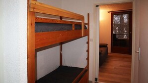 A bunk bed in a room with a wooden floor and a door leading to another room. - 300m from ski slopes, 4th floor, view valley, balcony, tv, 22m², Les Orres (Les Orres)
