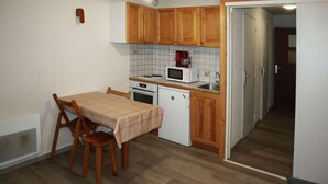A compact kitchen with wooden cabinets, a microwave, a stove, and a small sink. - 300m from ski slopes, 4th floor, view valley, balcony, tv, 22m², Les Orres (Les Orres)