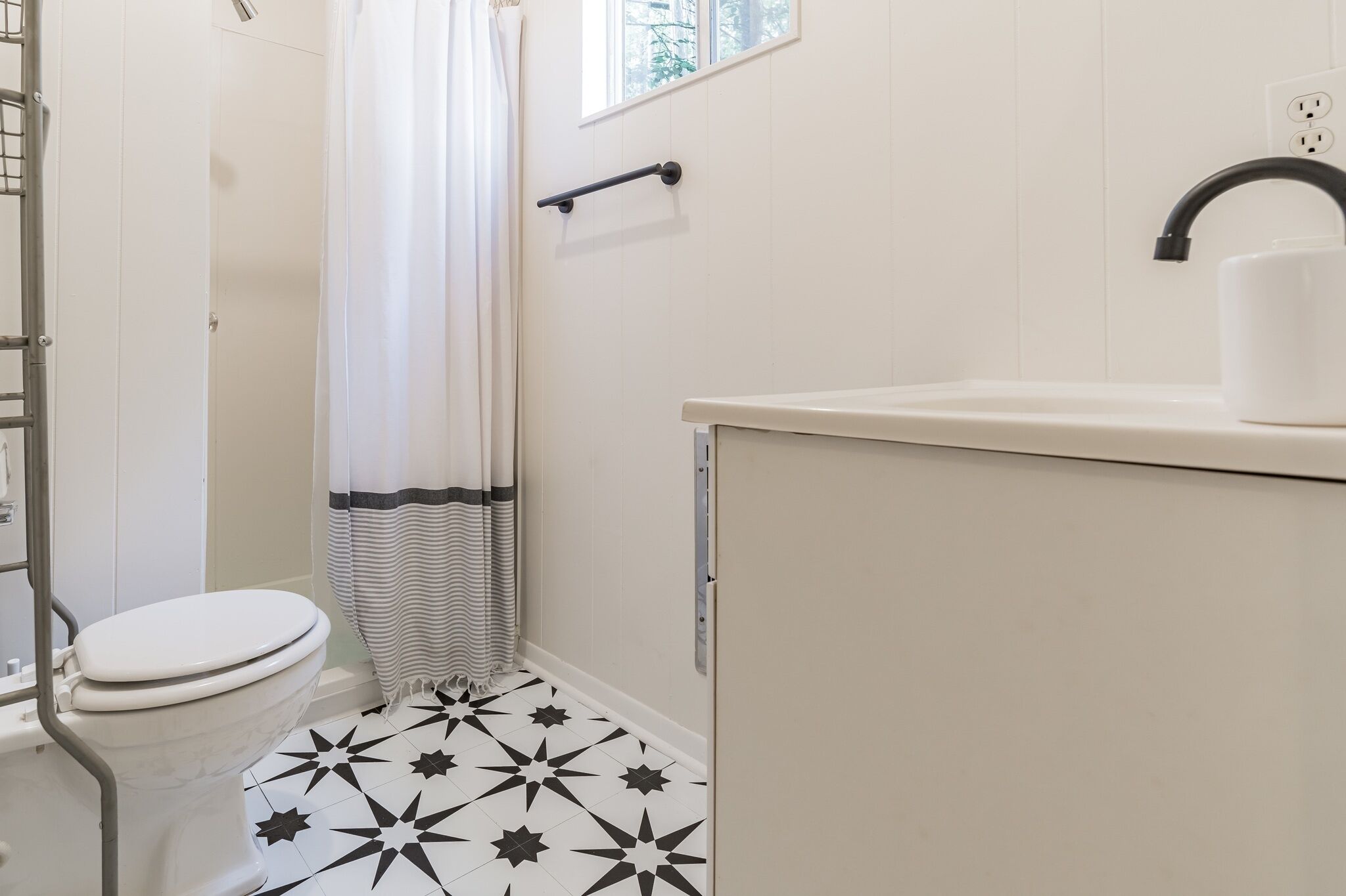 A bathroom with a toilet, a shower, and a sink.