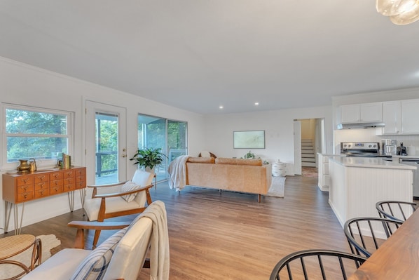 Une cuisine moderne avec des meubles blancs, un îlot central et un coin repas comprenant une table et des chaises en bois.
