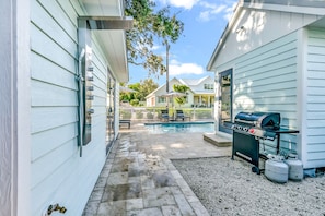 A backyard with a swimming pool, a barbecue grill, and a covered patio area.