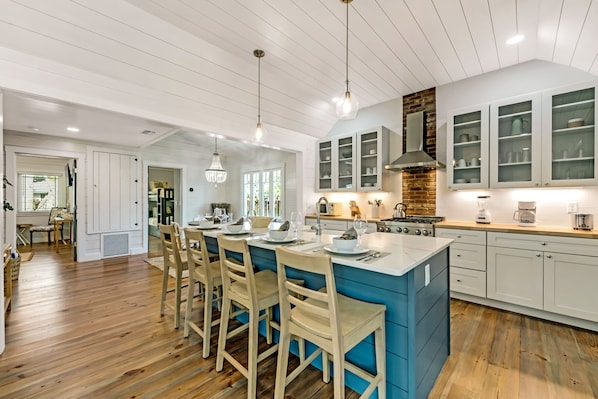 A modern kitchen with a central island, white cabinetry, and a blue accent wall.