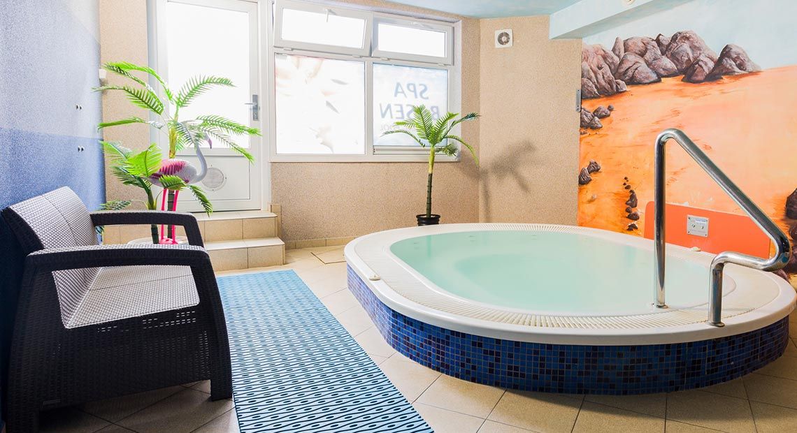 Een kamer met een ruim bad, een bank en een raam met uitzicht op het strand.
