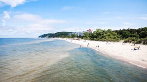 Une plage avec une eau claire, un rivage sablonneux et des bâtiments en arrière-plan.