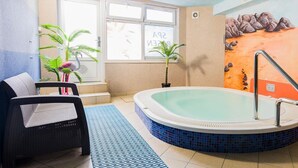 A room with a large bathtub, a sofa, and a window with a view of the beach. - Rezydencja Korab (Międzyzdroje)