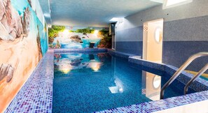 Relax by the pool with a clear view of the water's edge, surrounded by a mural of a natural landscape.