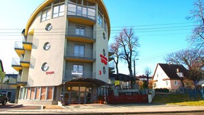 Un immeuble à plusieurs étages doté d’une façade incurvée, de balcons et d’une entrée au niveau du sol.