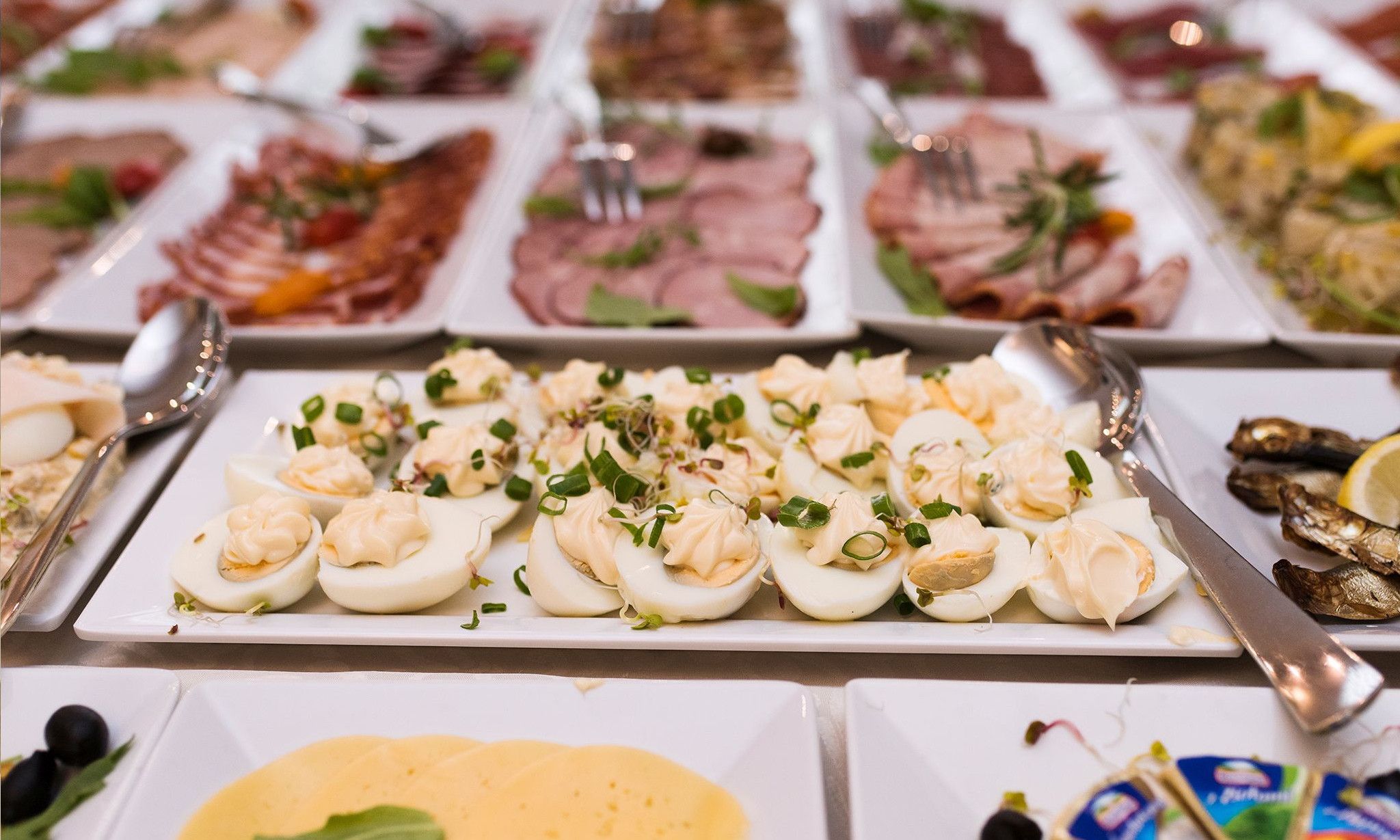 Un bufé con diversos platos, entre ellos huevos rellenos, mariscos y otras entradas.