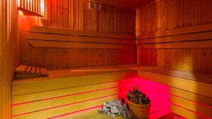 Un sauna avec des bancs en bois et un seau rempli de pierres.