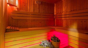 Un sauna avec des bancs en bois et un seau rempli de pierres.