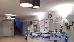 Un comptoir d’accueil avec une horloge, des affiches d’information et une décoration de Noël.