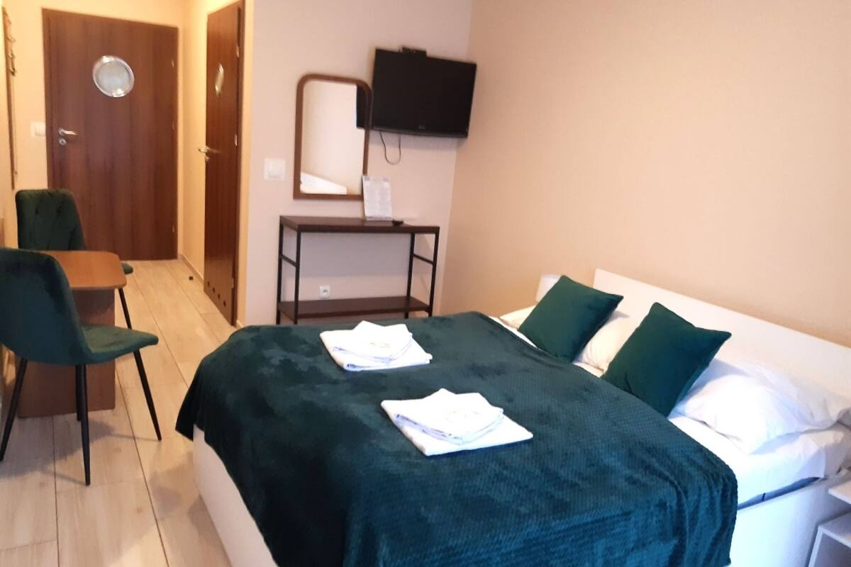 Una habitación de hotel con cama, escritorio, silla, televisor y puerta.