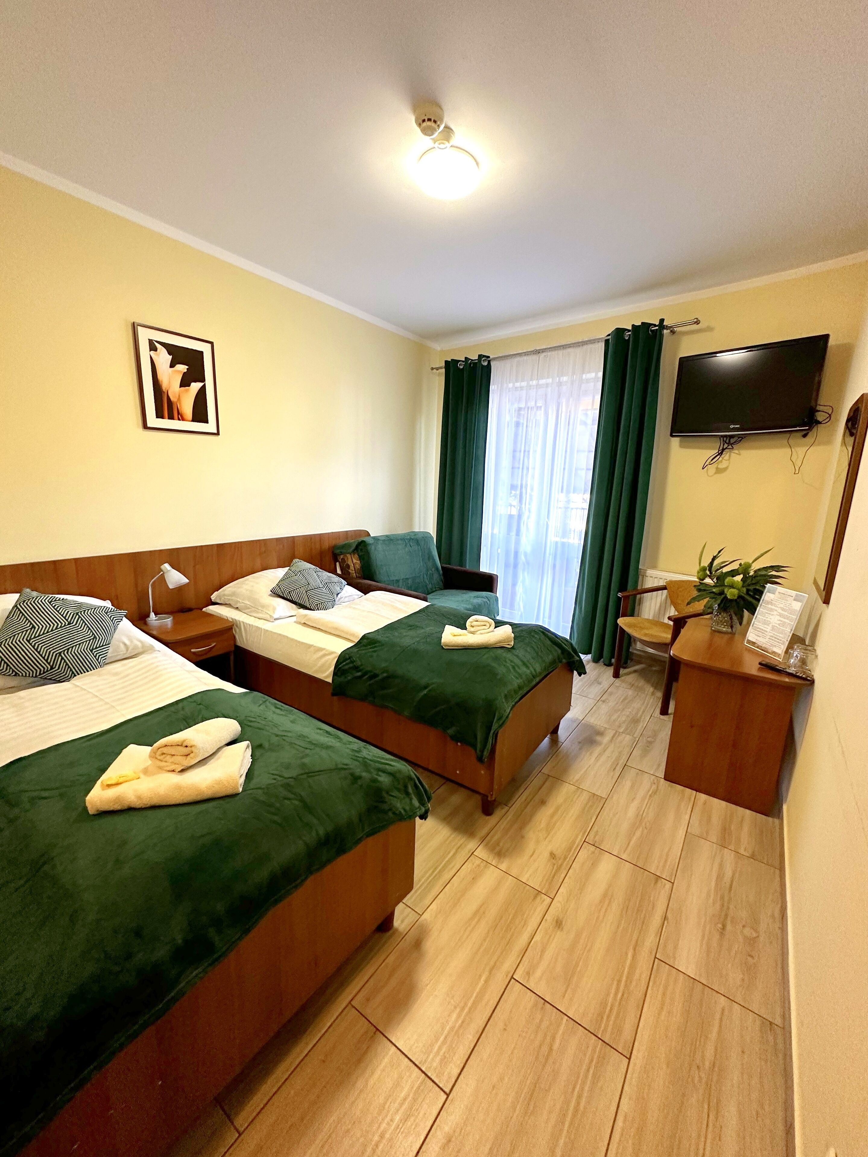Habitación de hotel con dos camas, un escritorio, un televisor y una ventana con cortinas.