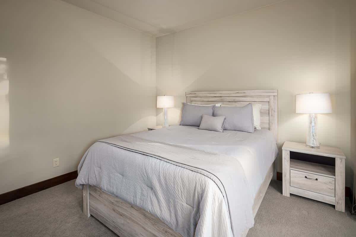 A bedroom with a bed, two bedside tables, and a nightstand.