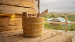 A wooden bucket with a rope handle on a wooden deck with a view of green fields and a building in the background. - Goldfinch Yurt with hot tub, Hawes, Yorkshire Dales (Askrigg)