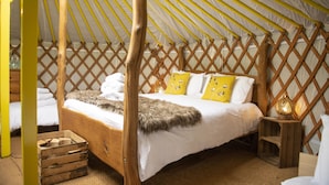 A room with a four-poster bed, wooden headboard, and a yellow and white striped ceiling. - Goldfinch Yurt with hot tub, Hawes, Yorkshire Dales (Askrigg)
