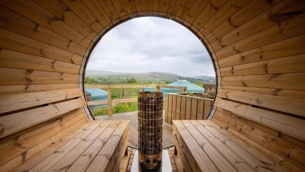 A sauna with wooden benches and a circular opening to the outside. - Goldfinch Yurt with hot tub, Hawes, Yorkshire Dales (Askrigg)