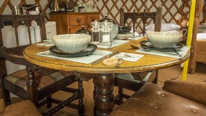 A round wooden table with two bowls, salt and pepper shakers, and a knife on a placemat. - Goldfinch Yurt with hot tub, Hawes, Yorkshire Dales (Askrigg)