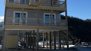 Un edificio de varios pisos con terraza de madera y barandas, que cuenta con varios balcones y una escalera.