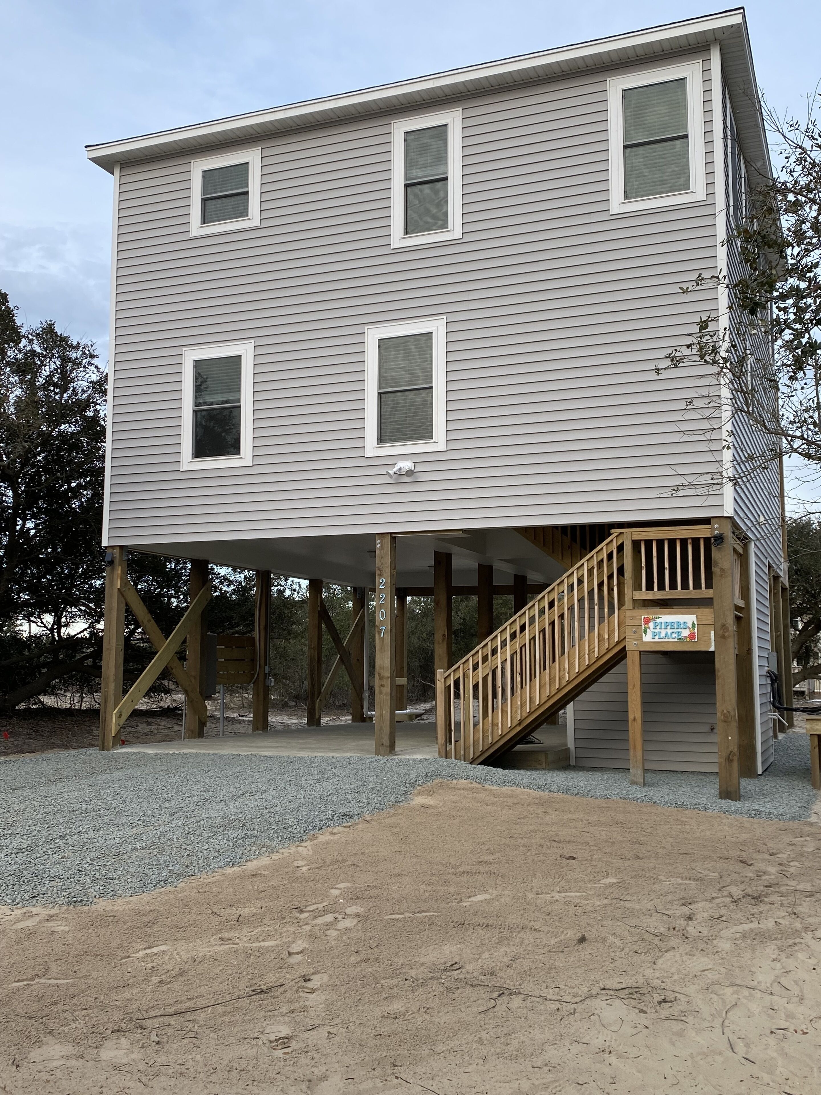 A two-story building with a wooden deck and a staircase leading to a covered area.