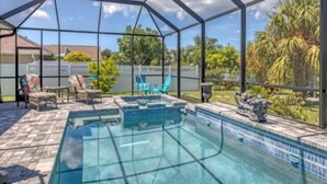 Une piscine couverte, protégée par une structure en verre, entourée de mobilier d’extérieur et offrant une vue sur le jardin arrière.