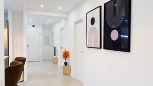Ein Flur im modernen Stil, mit einer Sitzecke, zwei Stühlen, einer Zimmerpflanze und zwei gerahmten Kunstwerken an der Wand.
