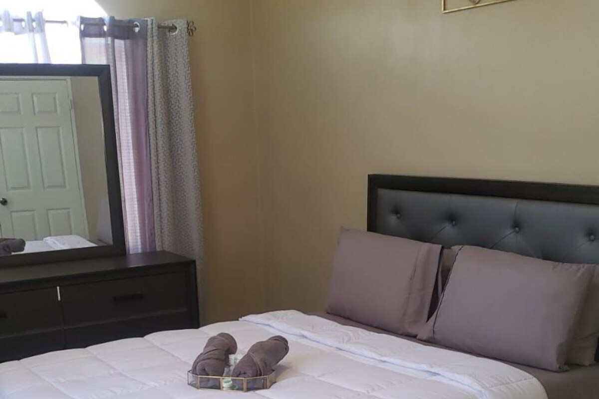A bedroom with a bed, a nightstand, a mirror, and a wall decoration.